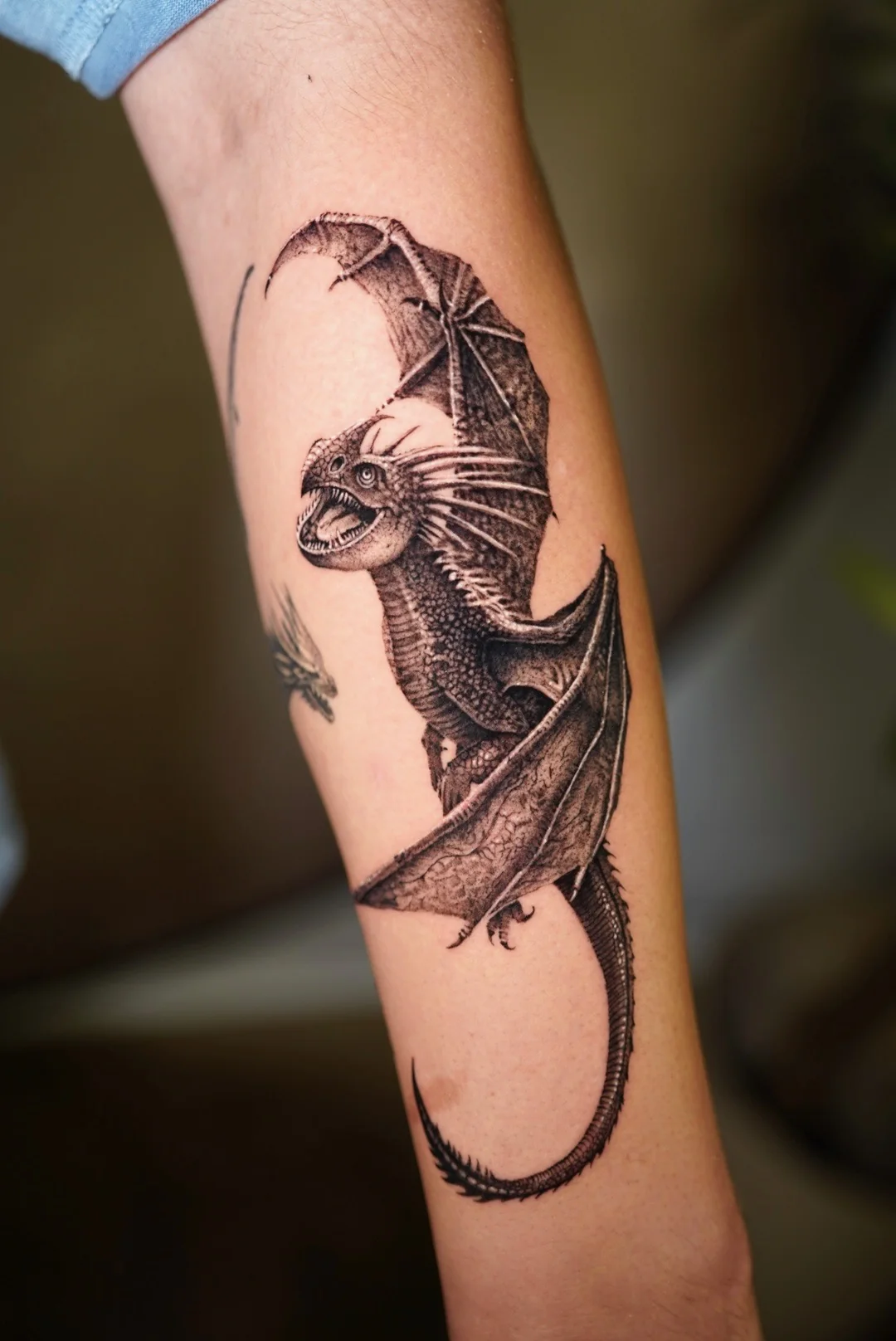Bat with spread wings tattooed along a forearm