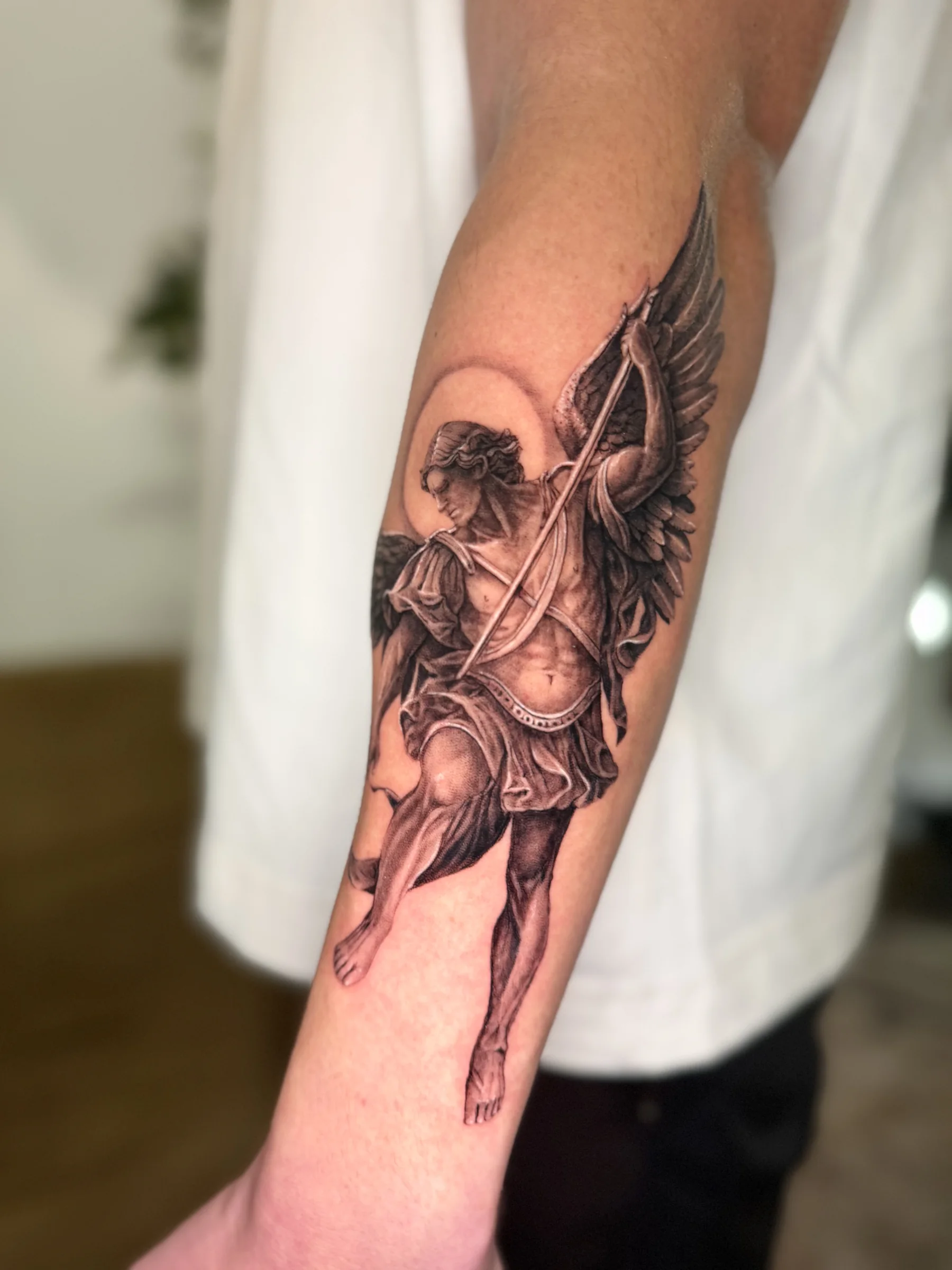 Cupid drawing a bow, tattooed on a forearm