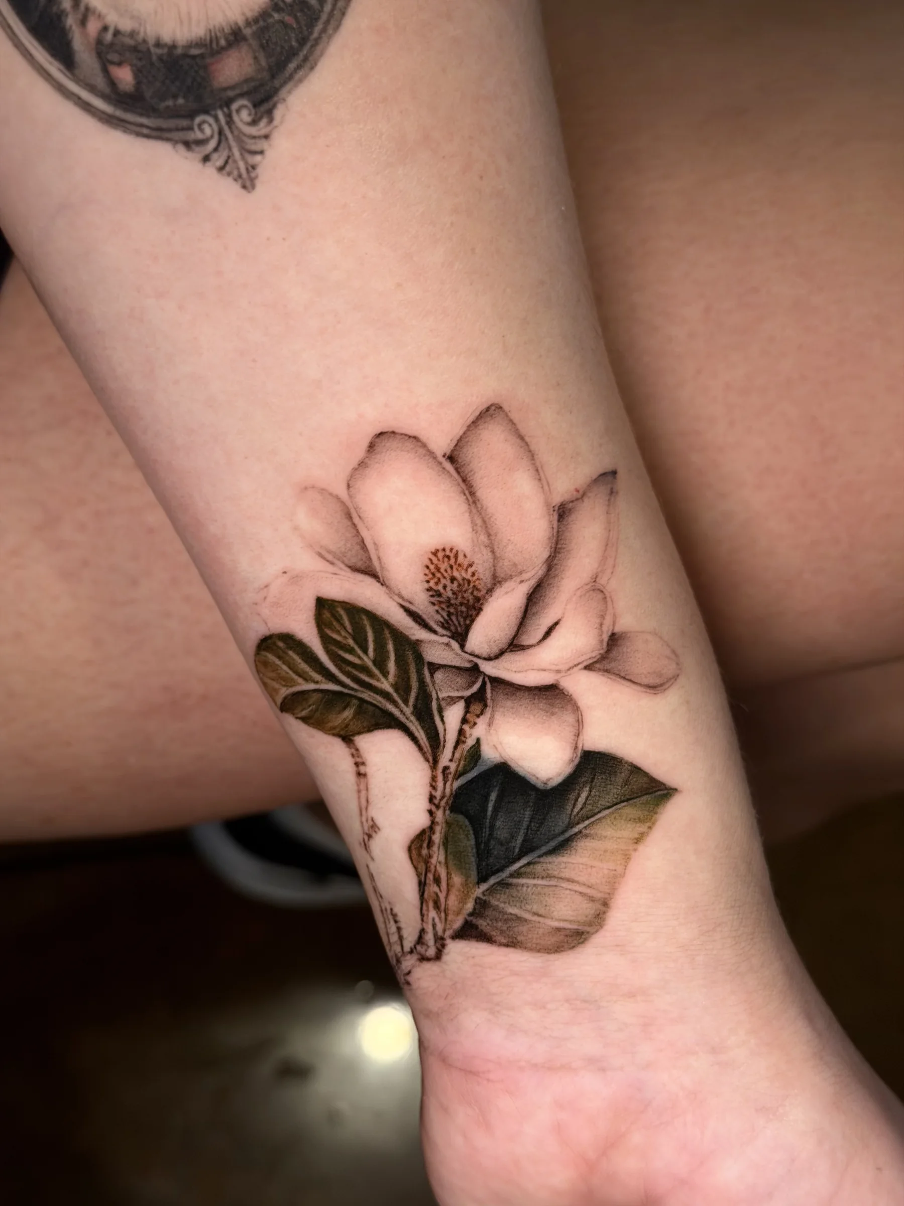 Magnolia flower tattoo wrapping a wrist
