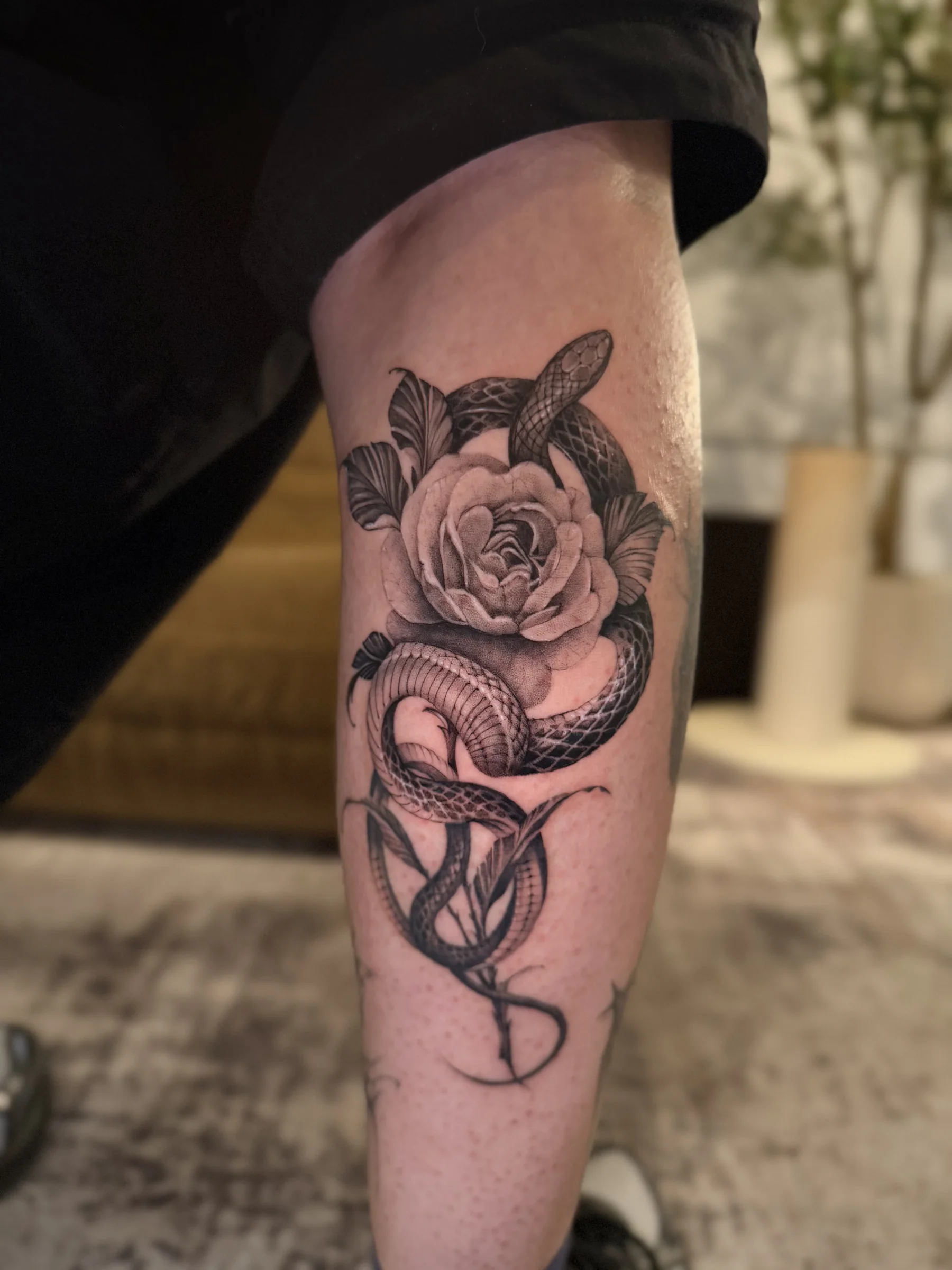 Snake wrapped around a rose on a lower leg